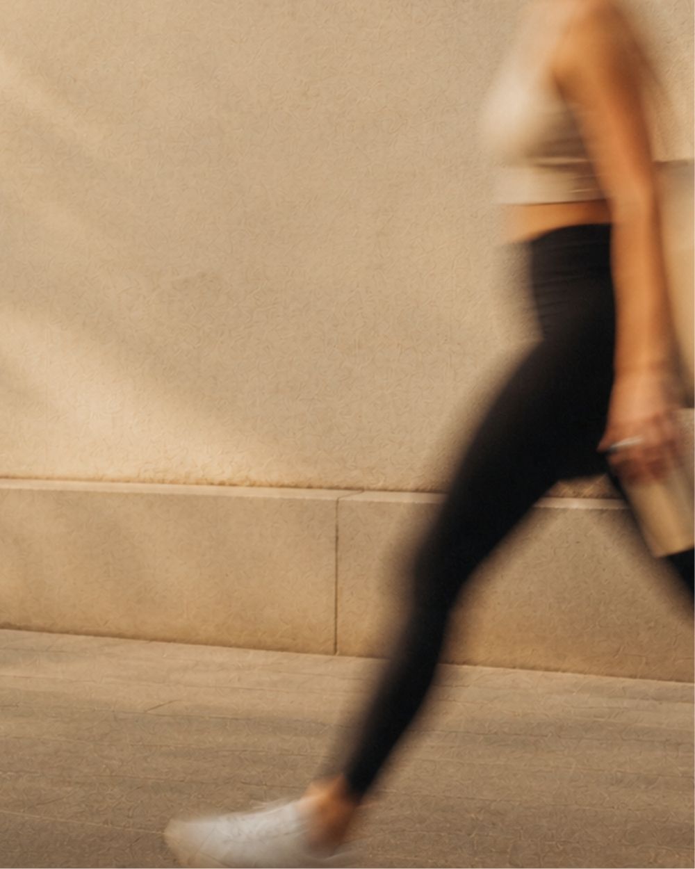 Silhouette en mouvement d'une femme marchant le long d'un mur en pierre claire